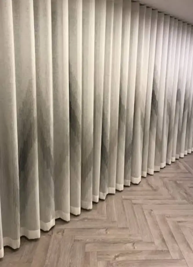 Pinch-pleat curtains across a large window